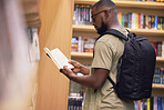 Education student with book in a library at university, college or school reading or doing research. Scholarship, learning and study knowledge and black man with print books on shelf and backpack