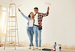 Portrait of happy couple painting the new living room in a home or apartment. Man and woman with paintbrush to decorate a wall color and renovation the house interior with smile or happiness together