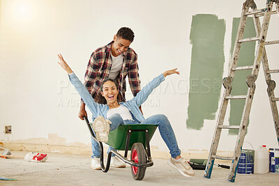 Buy stock photo DIY, painting and happy couple smile while moving into new home, real estate property house or building. Love, creative man and woman on wheelbarrow interior design and renovation work on room wall