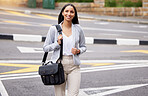 Business woman crossing the street during her walk to work with a briefcase bag outdoors in summer. Happy, corporate and professional employee taking stroll to the company office building in the city