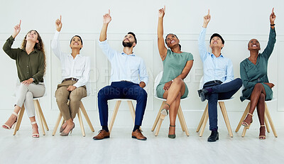 Buy stock photo Business, team and office in teamwork collaboration sitting and pointing up together in solidarity at the workplace. Group of creative people in diversity with hands, finger gesture for work success.
