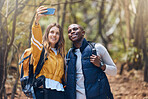 Hiking, diversity and couple taking a selfie with a phone while they smile, happy and travel in nature forest. Trekking, love and romance on adventure journey date with trees, earth and leaf growth