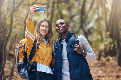 Buy stock photo Hiking, diversity and couple taking a selfie with a phone while they smile, happy and travel in nature forest. Trekking, love and romance on adventure journey date with trees, earth and leaf growth
