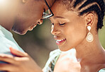 Closeup of a happy couple hugging in nature while on a romantic picnic date in the park. Care, love and young man and woman bonding while embracing each other in an outdoor garden during spring.