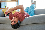 Headphones, phone and woman upside down on sofa in home streaming music, radio or podcast. Relax, mobile and happy female on couch with smartphone on social media, texting or web browsing in house.