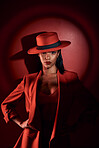 Spotlight, red suit and woman with fashion from 90s, elegant clothes and vintage on a studio background. Creative, dark and portrait of a retro, confident and classy model with a sexy aesthetic