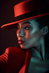 Fashion, dark and stylish woman in a studio with a seductive, vintage and elegant outfit. Sensual, fashionable and mysterious African female in a red suit posing while isolated by a black background.