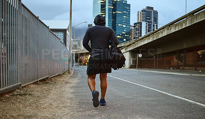 Buy stock photo Fitness, black man and walking on city street after running, exercise and gym workout with a hoodie at night. Back of a male athlete in urban Miami for a walk and cardio training with a duffle bag