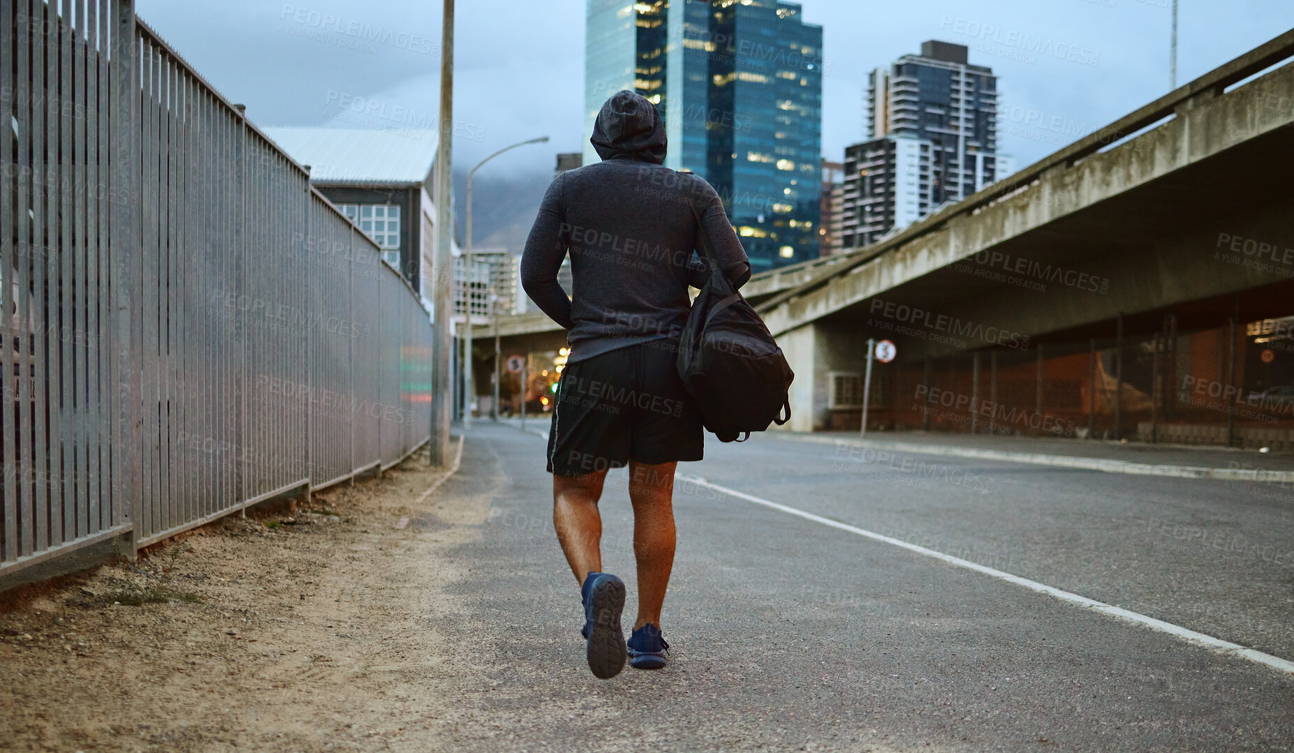 Buy stock photo Fitness, black man and walking on city street after running, exercise and gym workout with a hoodie at night. Back of a male athlete in urban Miami for a walk and cardio training with a duffle bag