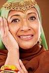 Portrait, Islamic woman and fashion with jewelry, smile and natural beauty on brown studio background. Muslim female, Arabic lady and traditional hijab with cultural outfit, cosmetics and makeup.