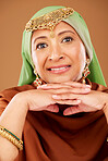Portrait, Islamic woman and fashion with culture jewelry, head scarf and mature beauty on brown studio background. Senior female, Muslim lady and traditional outfit, Arabic aesthetic and cosmetics.
