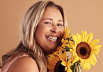 Mature woman and beauty portrait with flower bouquet and happy smile for natural skincare campaign. Wellness, cosmetics and healthy skin of latino person with sunflowers on beige studio background.