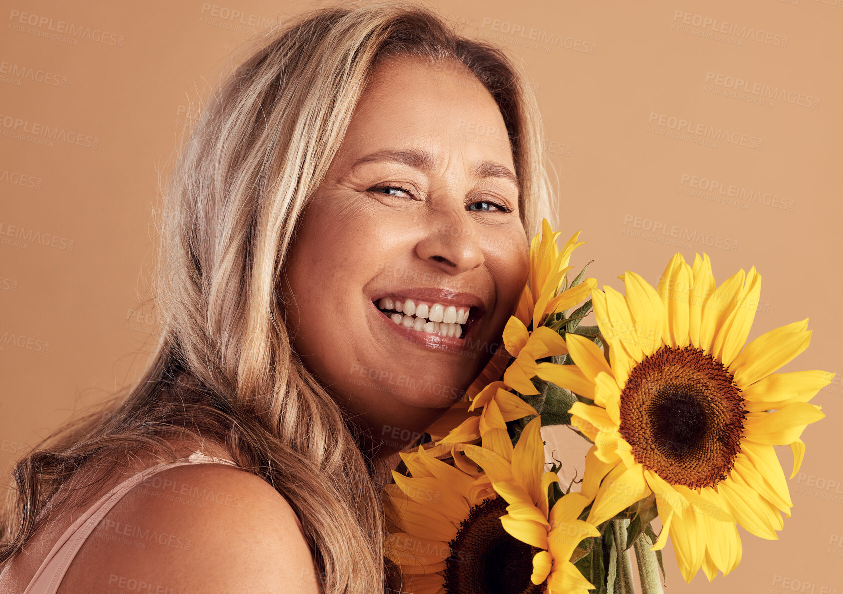 Buy stock photo Mature woman and beauty portrait with flower bouquet and happy smile for natural skincare campaign. Wellness, cosmetics and healthy skin of latino person with sunflowers on beige studio background.