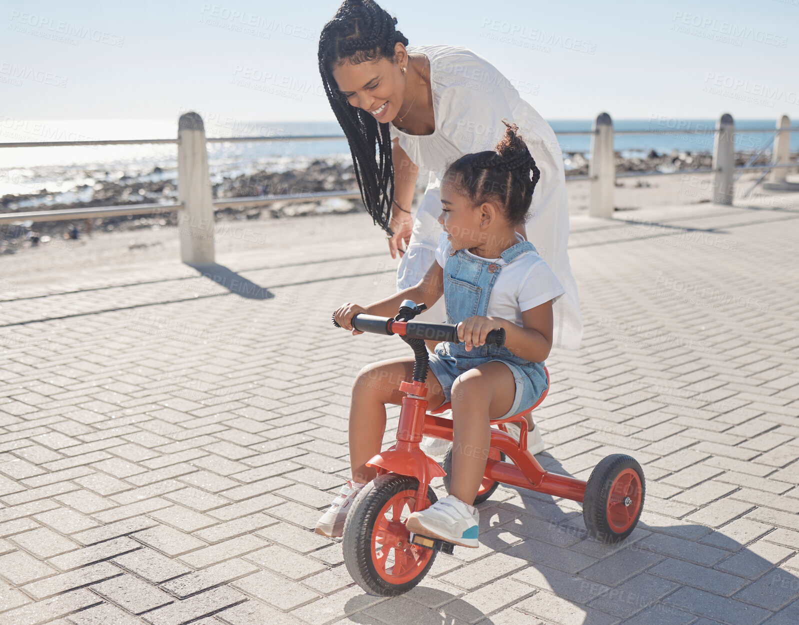 Buy stock photo Summer, ocean and mother with girl on bicycle enjoying holiday, vacation and quality time together on weekend. Family, love and mom with young child on bike for support, freedom and adventure by sea