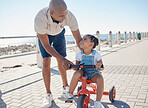 Father, girl child and tricycle at park, learning and happy in ocean sunshine on family vacation. Dad, daughter and happiness by sea promenade, teaching and smile on seaside holiday in San Francisco