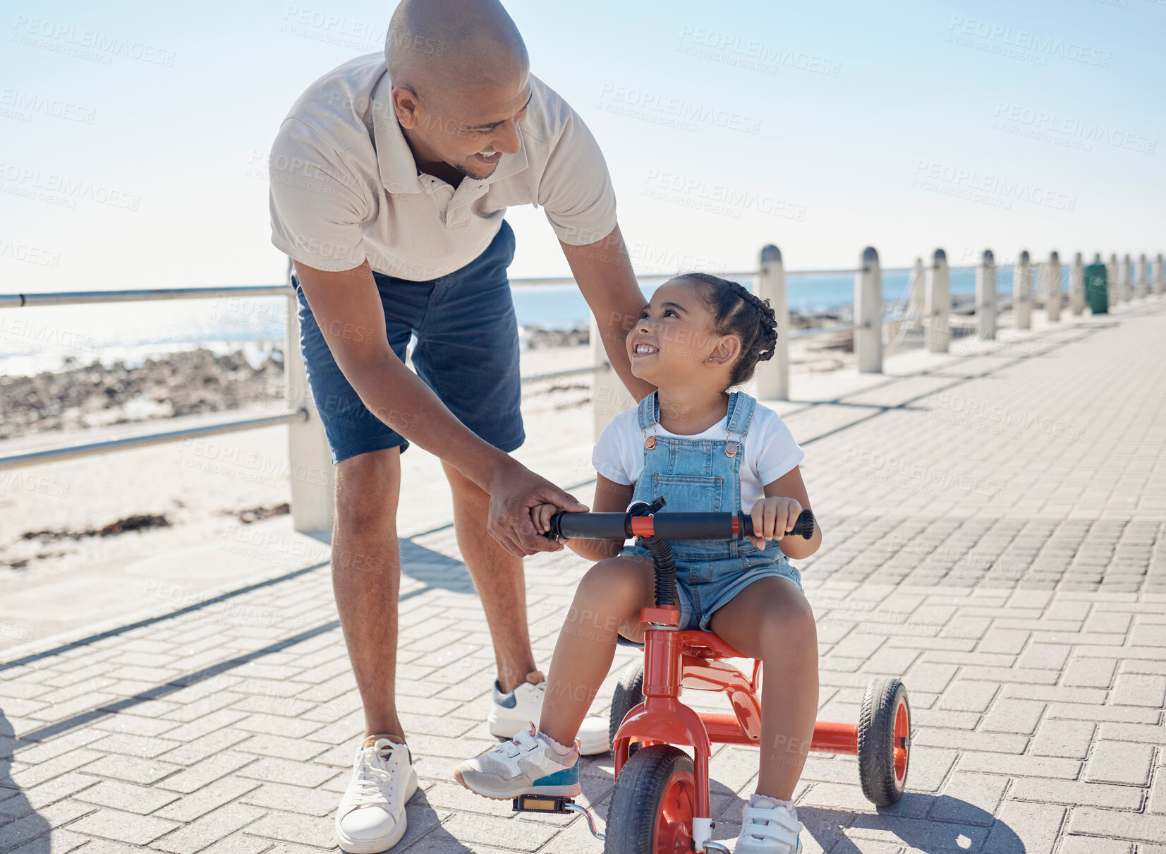 Buy stock photo Father, girl child and tricycle at park, learning and happy in ocean sunshine on family vacation. Dad, daughter and happiness by sea promenade, teaching and smile on seaside holiday in San Francisco