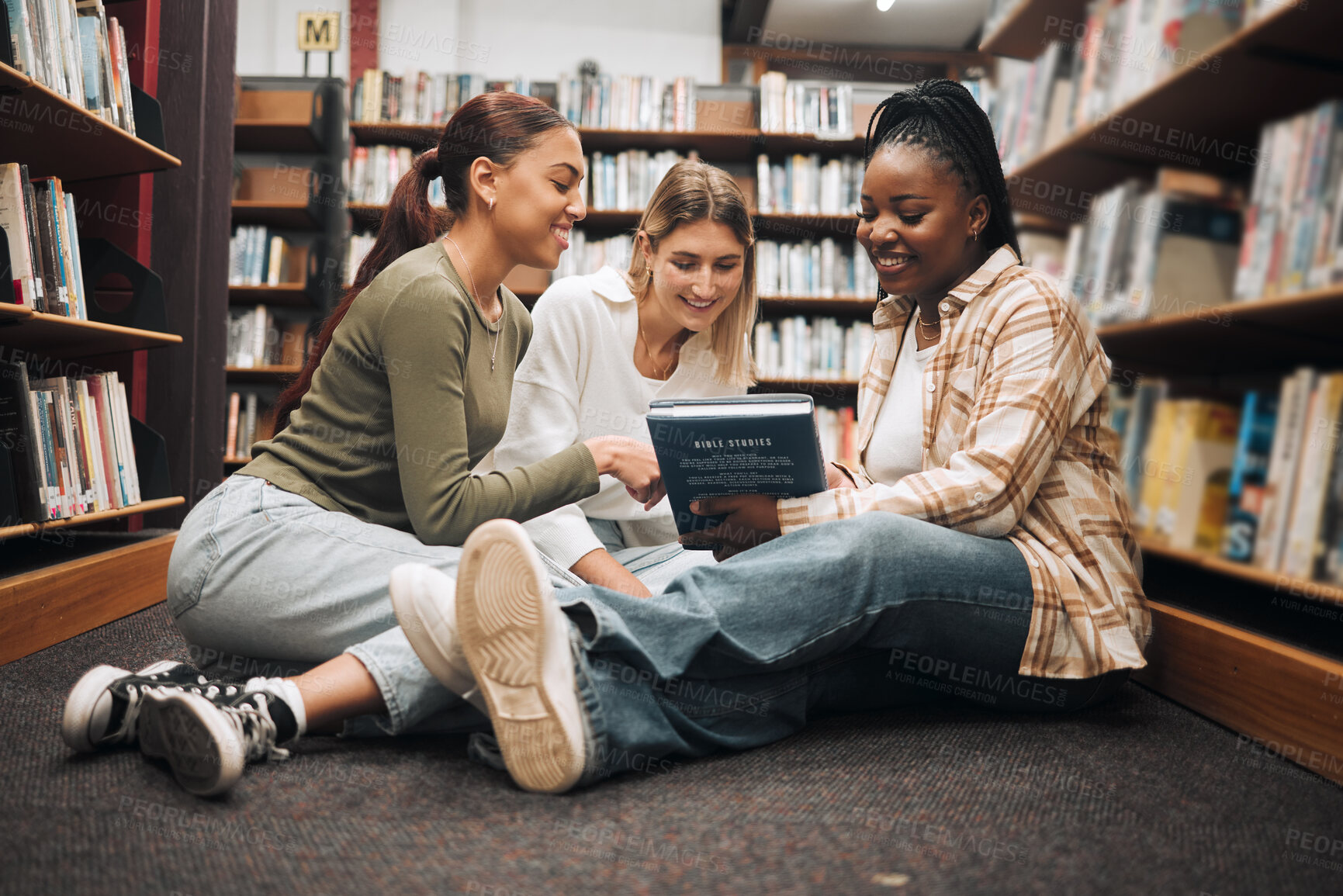 Buy stock photo Books, education and friends on a library floor for learning, research and homework assignment, happy and excited. Campus, women and university students bond on ground with book for exam preparation
