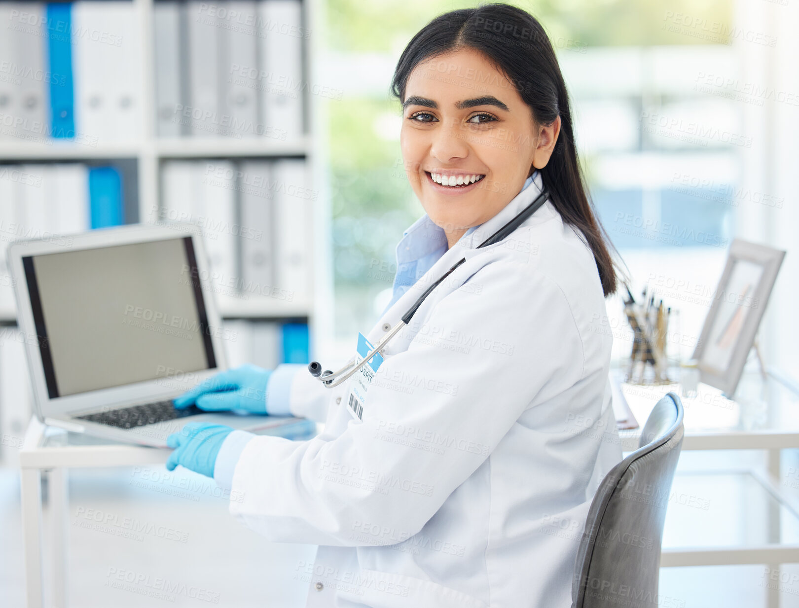 Buy stock photo Doctor, smile and working on laptop mockup with medical healthcare employee at her desk in hospital consulting room or office. Medicine or wellness woman professional in clinic on internet database