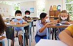 Covid learning with teacher and school students having lesson, study and education in class during pandemic. Educator helping, showing and talking to young kindergarten, preschool and elementary kids