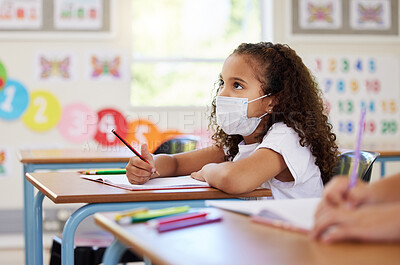 Buy stock photo Education, classroom and learning with covid face mask on girl doing school work, writing and reading at her desk in elementary class. Elementary child wearing protection to stop the spread of virus