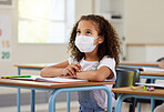 Child or student in class during covid, wearing a mask for hygiene and protection from corona virus flu. Little kindergarten, preschool or elementary school girl sitting in a classroom ready to learn