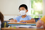 Face mask to protect from covid during pandemic, creative school student learning in class and writing in notebook in classroom. Boy sitting at a desk, doing education task and studying with books