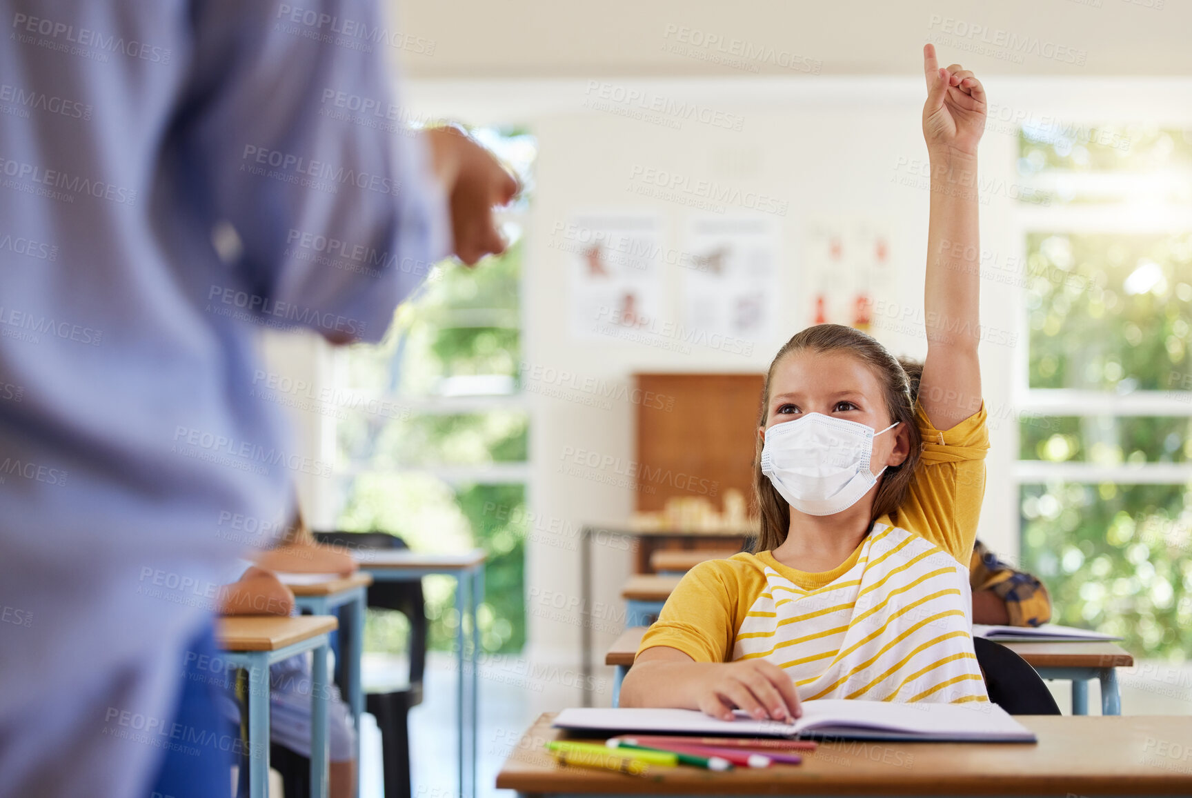 Buy stock photo Smart student with covid face mask asking teacher question about corona virus pandemic in a classroom or elementary school. Little girl child raising hand to answer healthcare related topic in class