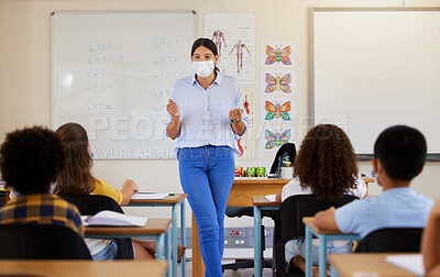 Buy stock photo Young female teaching after covid pandemic, in classroom with young children students, in face mask. Back to school for little kids learning their education from their teacher after quarantine