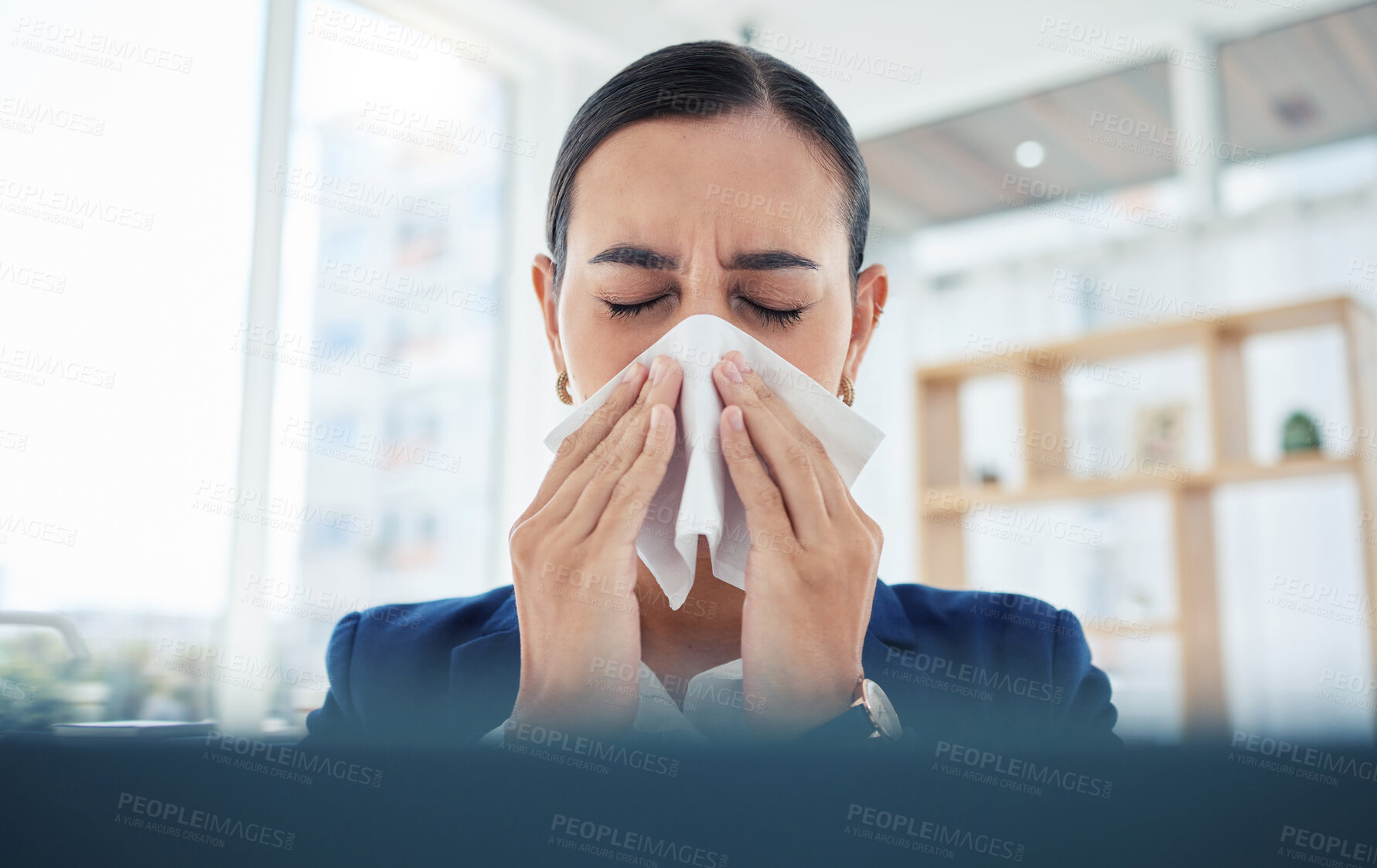 Buy stock photo Covid, virus and sick with a business woman blowing her nose with a tissue and sneezing while working in her office. Allergies, sneeze and flu with a female employee suffering from a cold at work