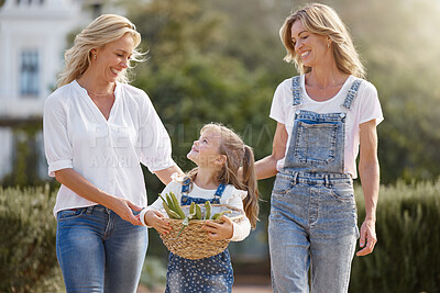 Buy stock photo Lesbian couple on an outdoor walk with their child for fresh air in a garden during spring. Happy lgbtq women bonding with their girl kid while having fun in nature after harvesting crops together. 