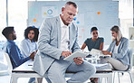 Businessman, leader or ceo with a tablet against the boardroom table after a meeting. Team or colleagues in the background planning and brainstorming for a startup project in an office boardroom
