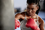 Woman, boxing and gym training workout for strong and motivated athlete fighter fitness. Hand coordination, focus and concentration for punching bag strike exercise in sports facility.

