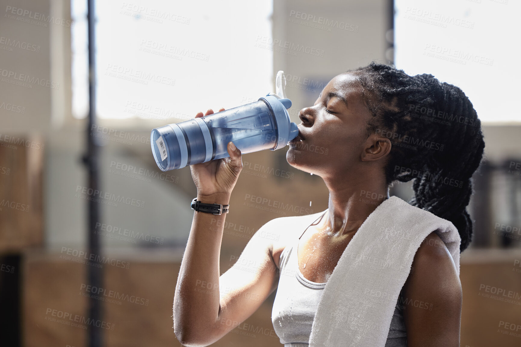 Buy stock photo Drinking water and relax after a fitness, workout and exercise training of a woman athlete. Female from Nigeria with sweat done reaching target cardio sports goal at a health, wellness and sports gym