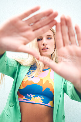 Buy stock photo Beautiful model, a triangle sign with fashion hands looking though it in bright, colorful clothes. Portrait of a young beautiful woman with artistic, trendy and funky style standing outdoors.