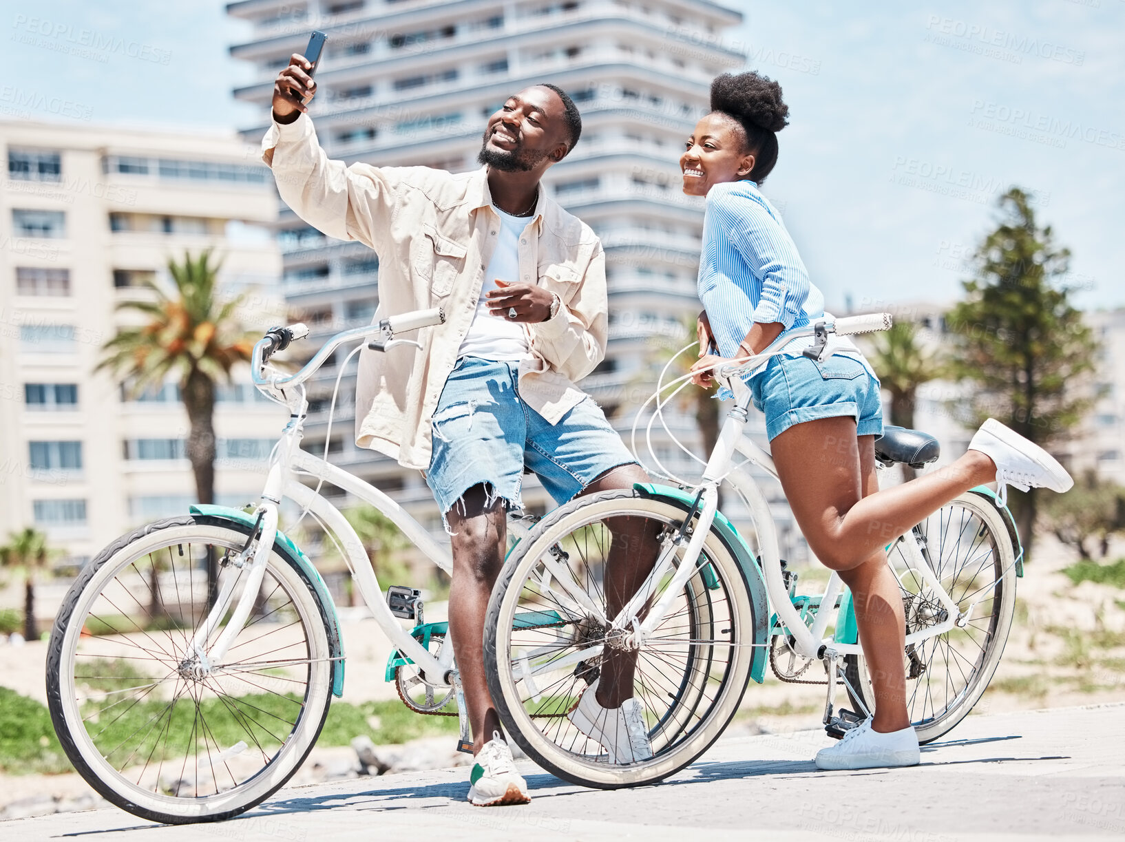 Buy stock photo Selfie, bike and date with a couple cycling on a promenade during summer with love, romance and affection. Bicycle, photograph and fun with a black woman and man outside and a city in the background