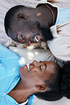 Love, happiness and black couple laying outdoors on the floor with blankets to relax in a park. Happy, care and African man and woman with a smile resting while on a date in nature by a garden.