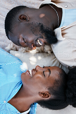 Buy stock photo Love, happiness and black couple laying outdoors on the floor with blankets to relax in a park. Happy, care and African man and woman with a smile resting while on a date in nature by a garden.