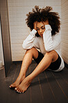 Stress, tired and mental health with young black woman sitting on bathroom floor of shower at home. Headache, depression and anxiety with female sad while alone with grief, fear or burnout