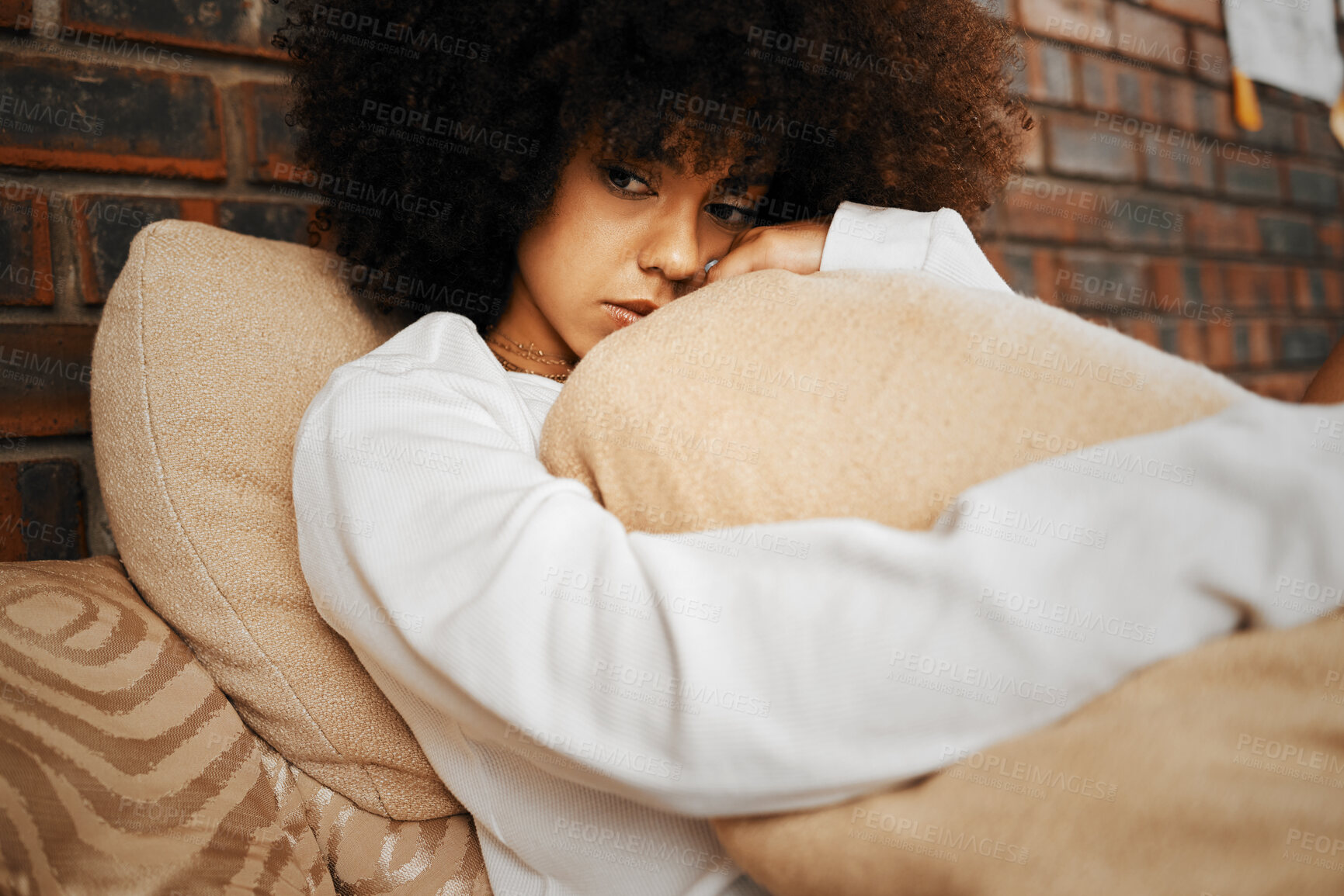 Buy stock photo Sad, depressed and lonely black woman with mental health problems hugging a pillow at home. Portrait of a African afro female in depression, stress and anxiety feeling unhappy living alone in a house