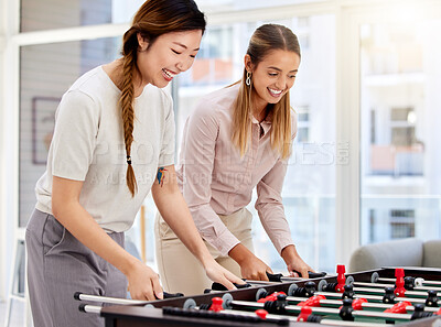 Buy stock photo Business women playing table soccer, laughing and having office fun at their corporate job. Diverse female colleagues bonding while competing in a friendly foosball game during a break together