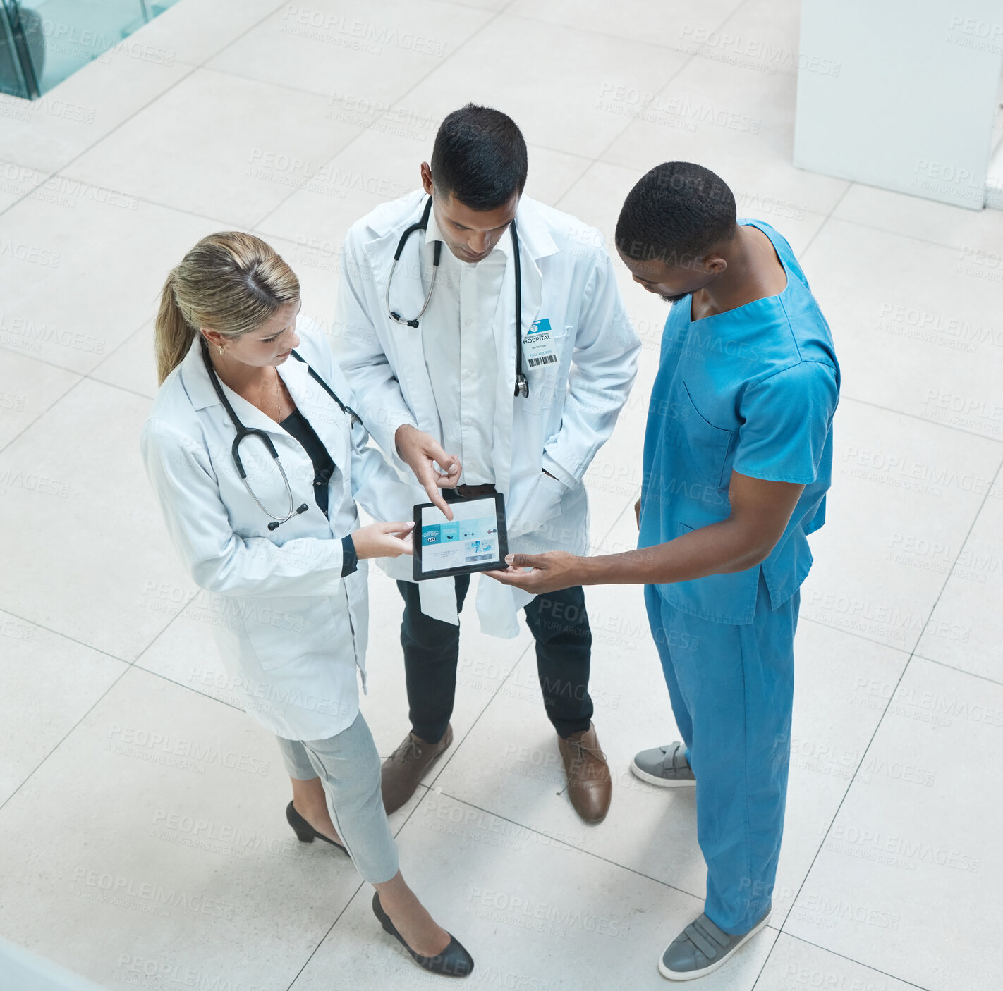 Buy stock photo Group of doctors working on digital tablet while standing in the hospital hallway and talking. Top view of healthcare employees analyzing test results and treatment in medicare clinic with technology