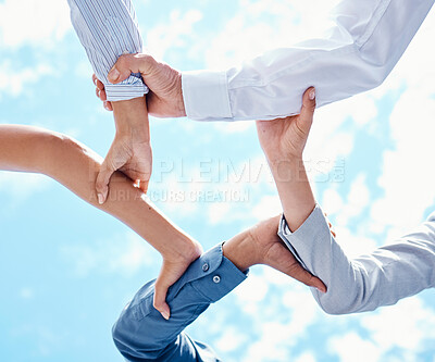 Buy stock photo Teamwork, hands and collaboration with a team of business people holding arms in a circle or huddle on a blue sky from below. Motivation, trust and support with a group in unity or solidarity outside