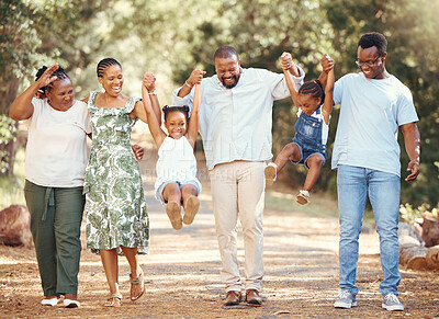 Buy stock photo Happy black family bonding and having fun at a park together, laughing and playful holding hands on active walk in nature. African American children enjoy time outdoors with parents and grandparents