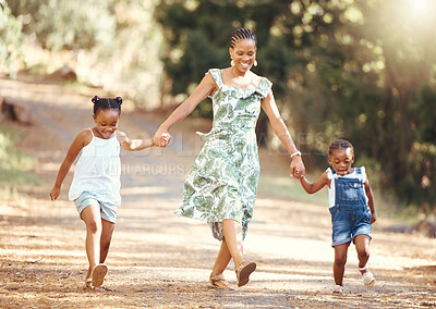 Buy stock photo Happy, mother and kids walking in a forest holding hands in nature in joyful happiness and smiling. Black family of a mom and her little girls bonding on a fun walk in the natural outdoor environment