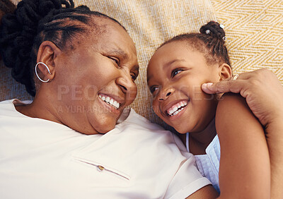 Buy stock photo Happy, smile and family of a black grandma and child in happiness relaxing and lying on a bed at home. Senior African grandmother and little girl in joyful, love and smiling together in the bedroom