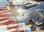 Feet or legs of friends with roller blade relax near lake water, ocean or sea after adventure, journey or skate ride. Skating community, team and club or people meeting for fun beach group travel


