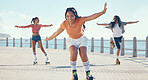 Friends, fitness and roller skating at the beach in summer as a group of young gen z girls and boy skate in freedom. Smile, happy and active people riding blades on the promenade on holiday vacation