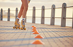 Woman roller skating with fitness cones outdoor on the promenade at the beach during summer. Girl practicing her skill while training a sports activity for exercise in nature at the ocean.
