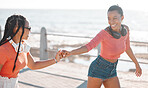 Freedom, friends and headphones with women roller skate at the promenade together by the sea for fun. Relax, music and summer with young females skating by the beach for wellness and bonding