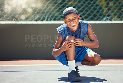Buy stock photo Child with a band aid on a knee injury from sports outside on a basketball court touching his bandage. Boy with a medical plaster hurt by accident while training or practicing for a game.
